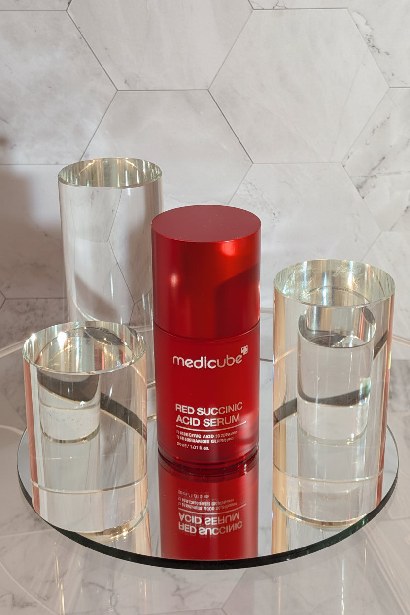 Medicube Red Succinic Acid Serum displayed in a luxury skincare setting, showcasing a lightweight Korean serum for acne and pore care.